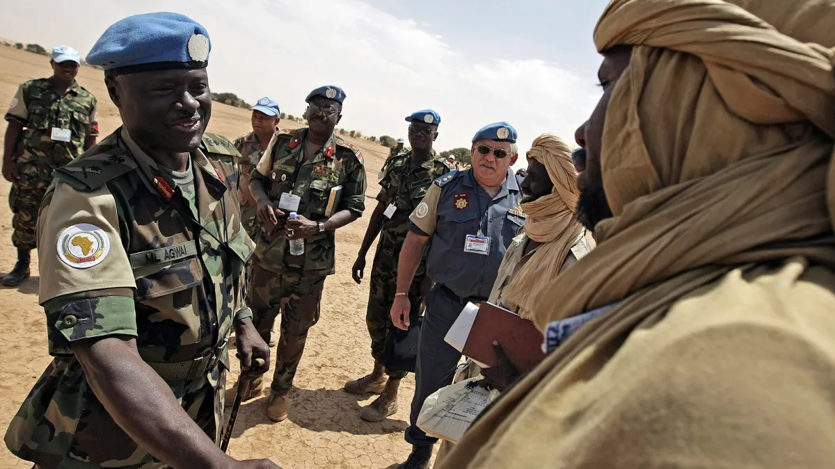 Peacekeeper and local man in traditional clothing shaking hands.